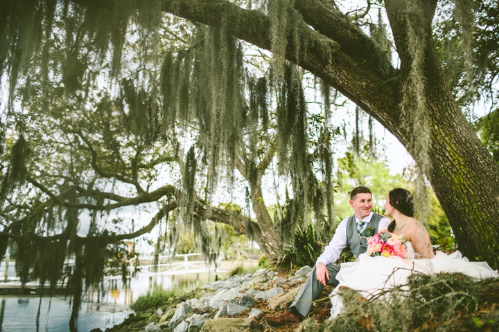 bride and groom sitting under moss tree