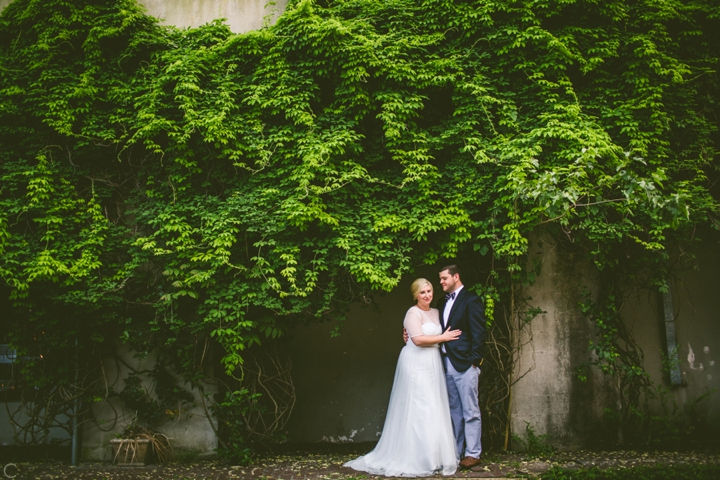 Bride and groom standing by ivy wall