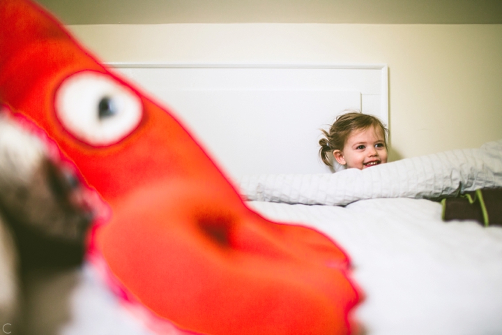 girl hiding behind bed