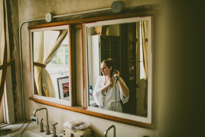 Bride curling hair in mirror