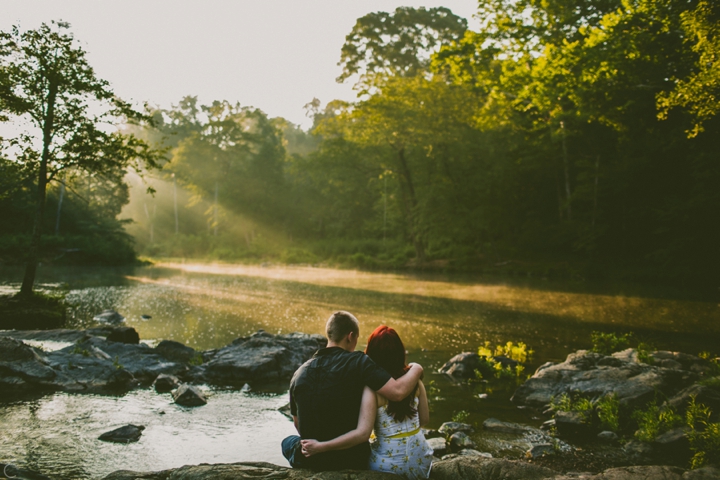 Couple with arms around each other watching sunrise