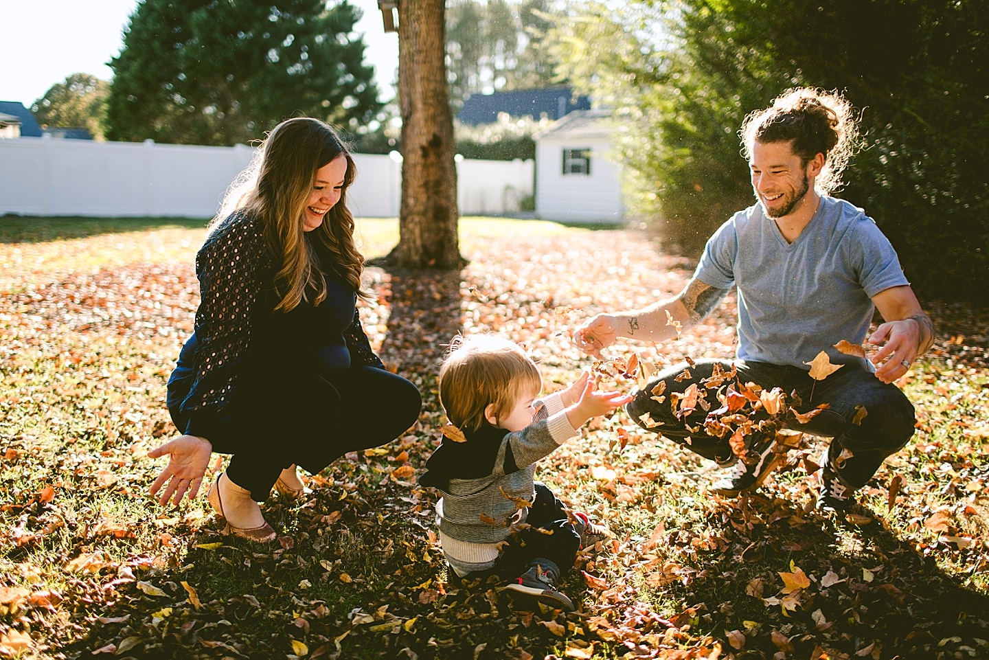 Parents throwing leaves with a child in the yard
