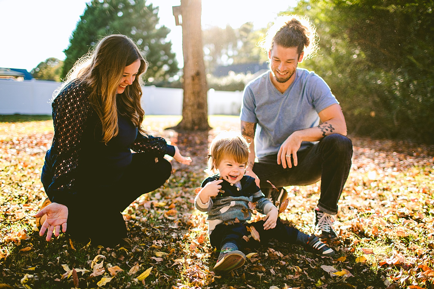 Parents throwing leaves with a child in the yard