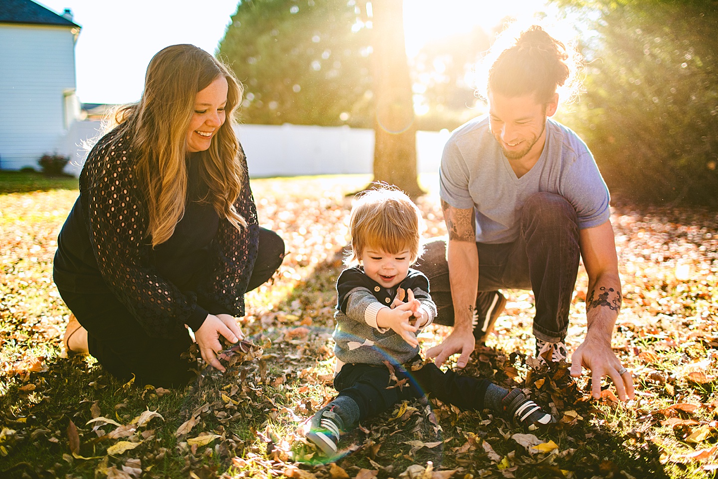 Parents throwing leaves with a child in the yard