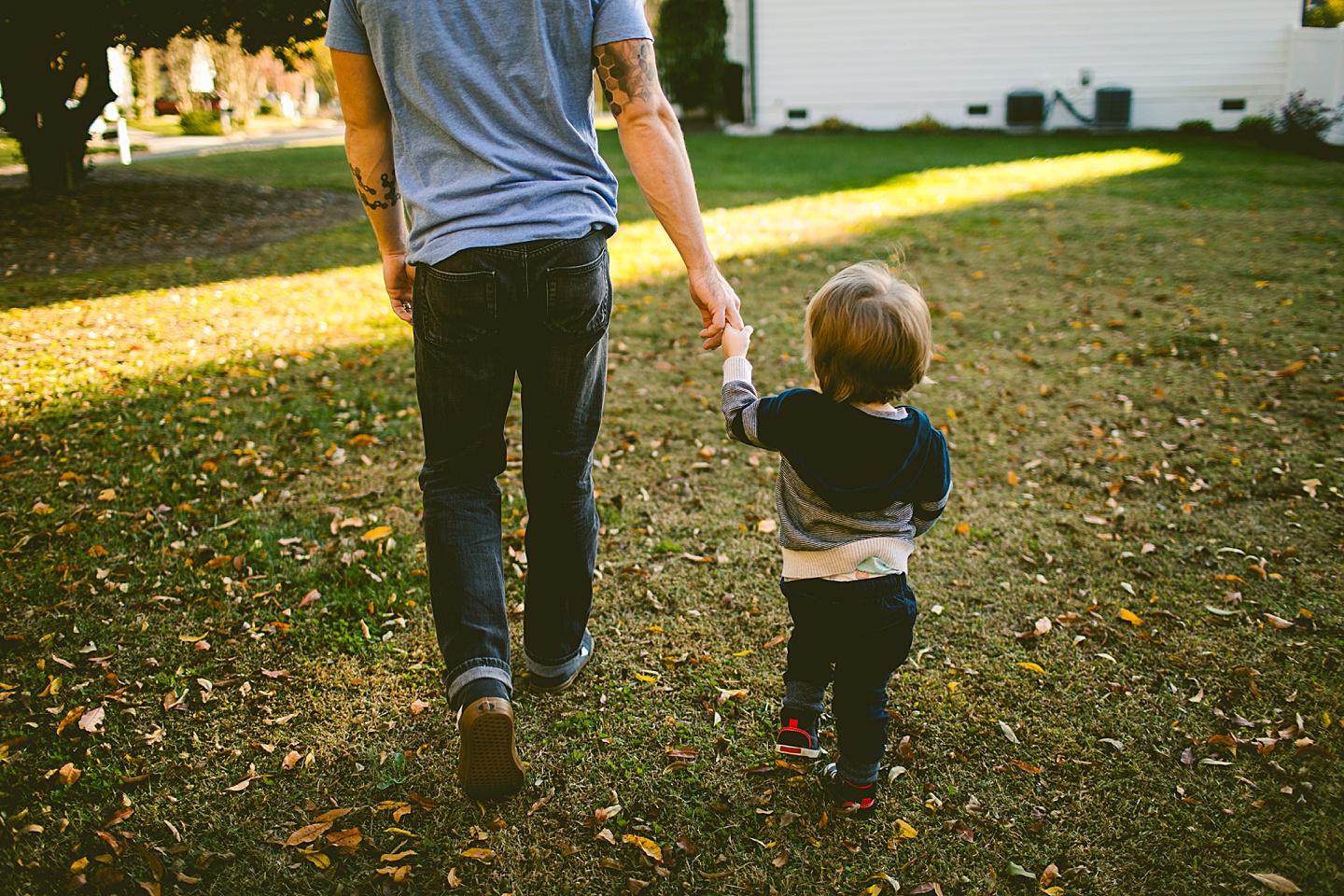 Toddler walking with his dad holding his hand