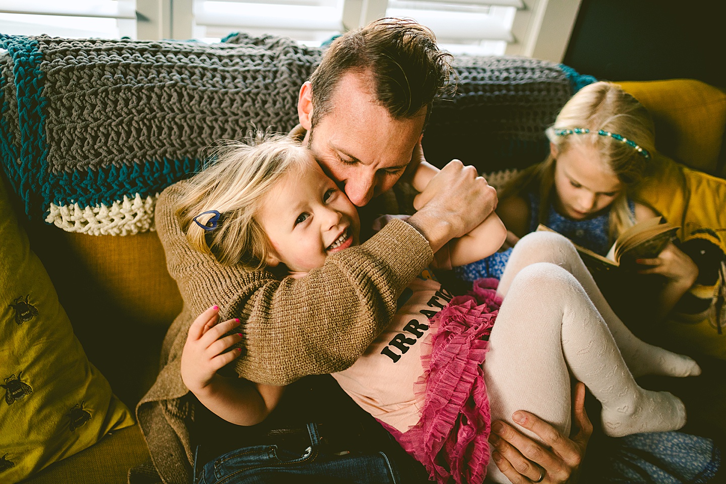 Family cuddling on couch in living room