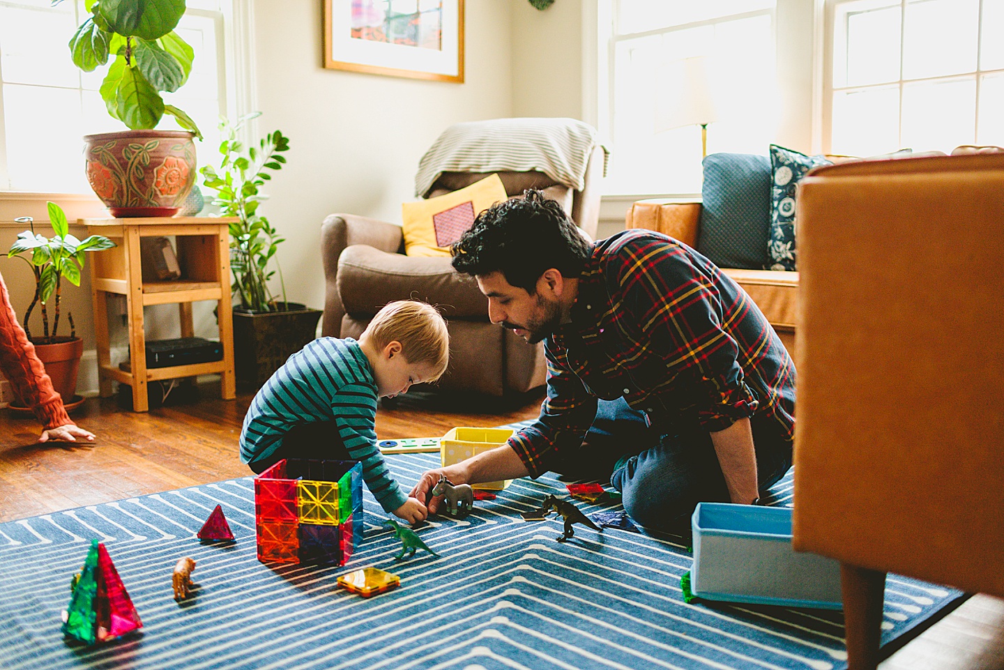 Dad playing with toy animals with son in living room