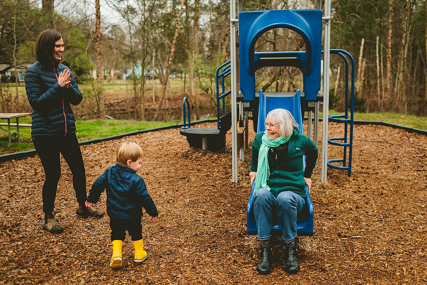Grandma using the slide at park while playing with grandson