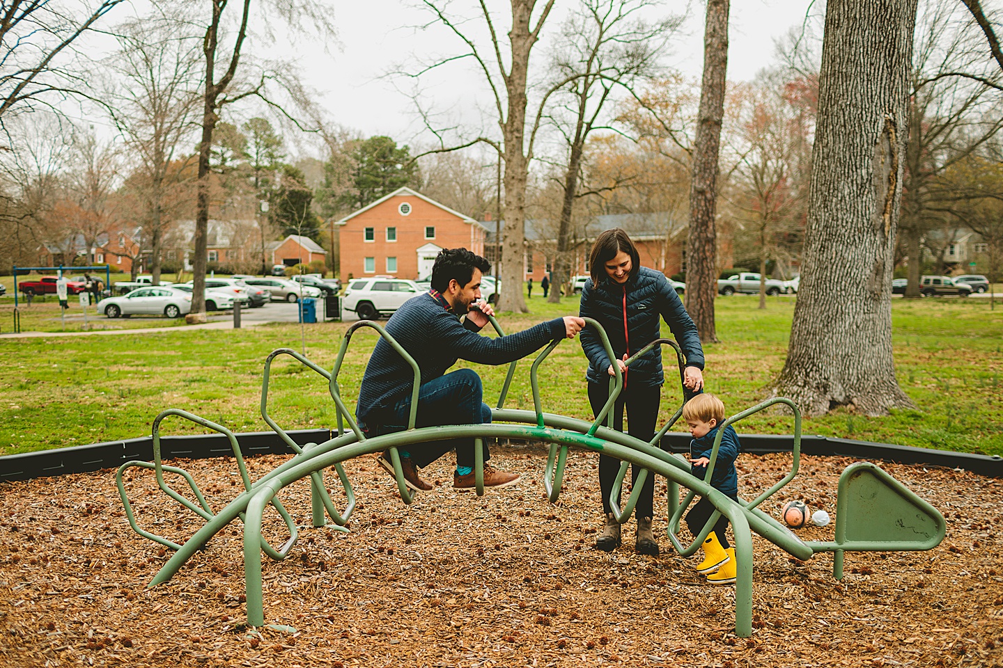 Family playing on dinosaur playground equipment