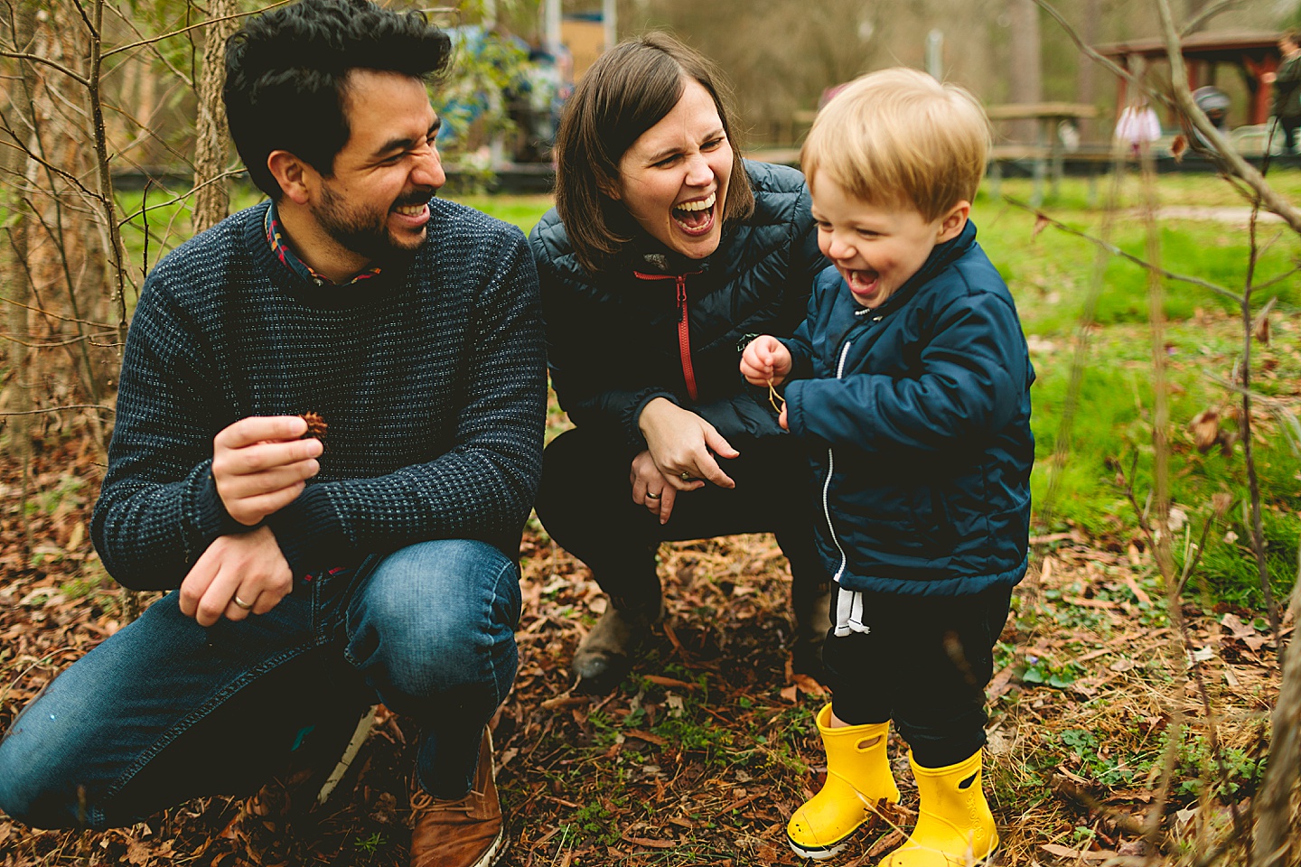 Family laughing while throwing pinecones into a pond