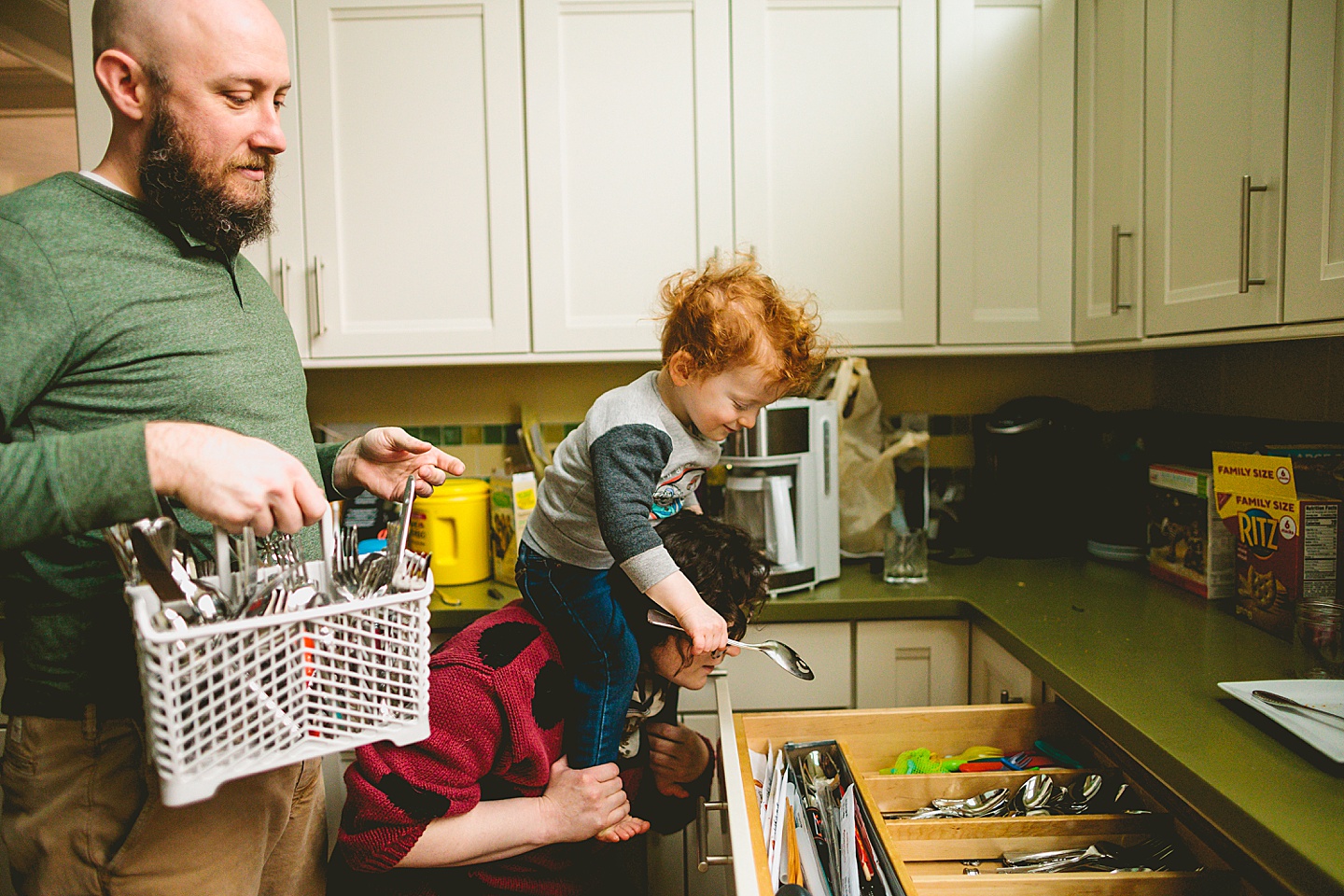 Toddler putting a spoon away in a kitchen drawer