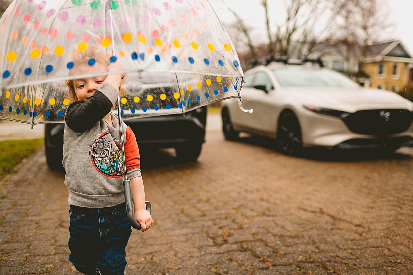Toddler walking around with umbrella in the rain