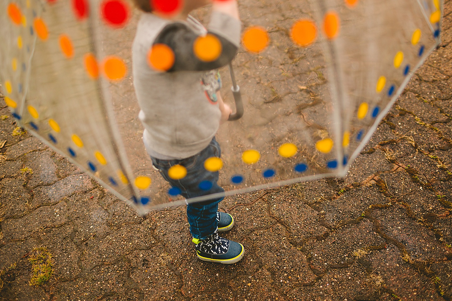 Toddler walking around with umbrella in the rain