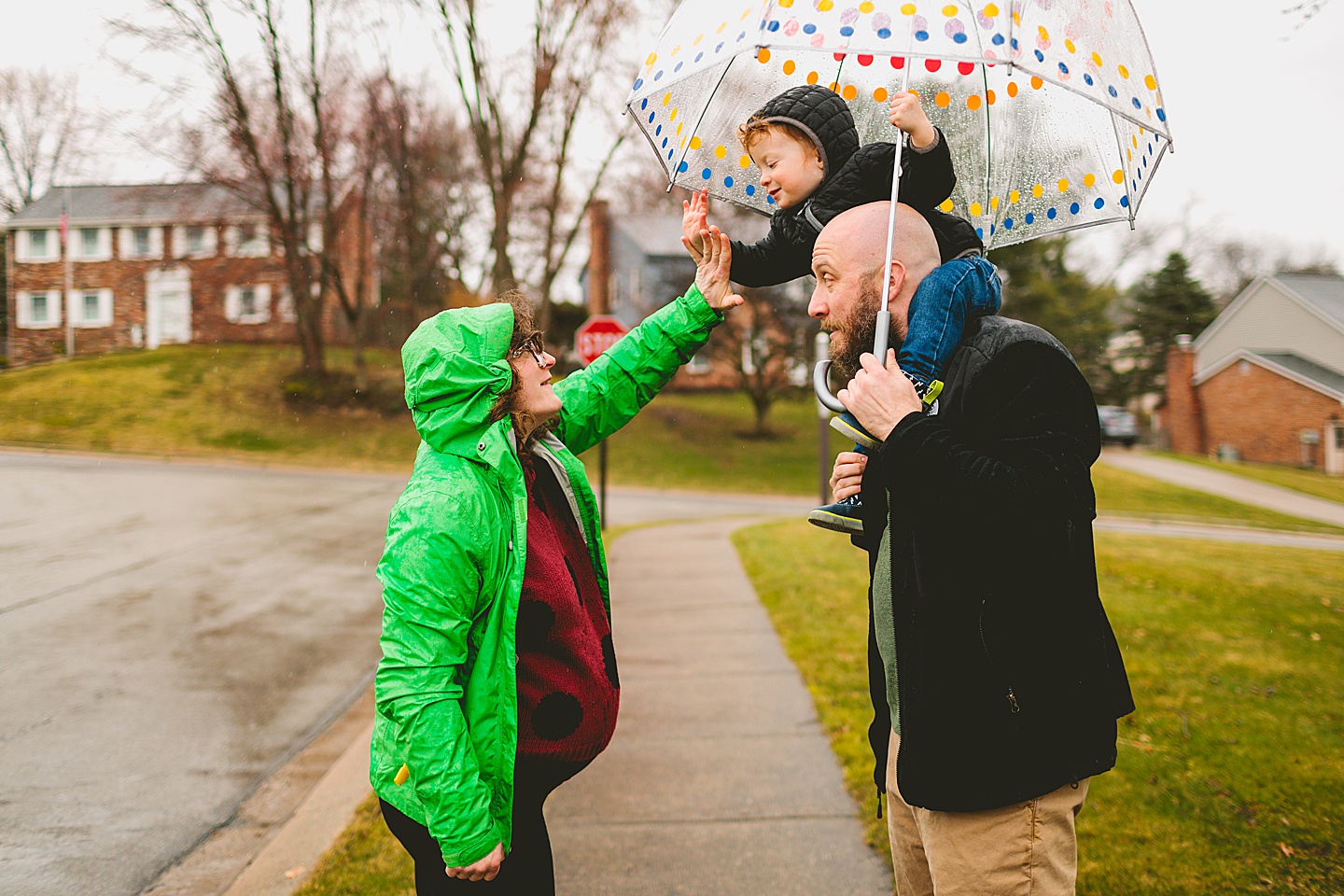 Parents taking a rainy day walk with toddler down the street