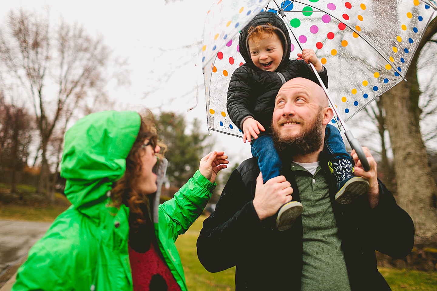 Parents taking a rainy day walk with toddler down the street