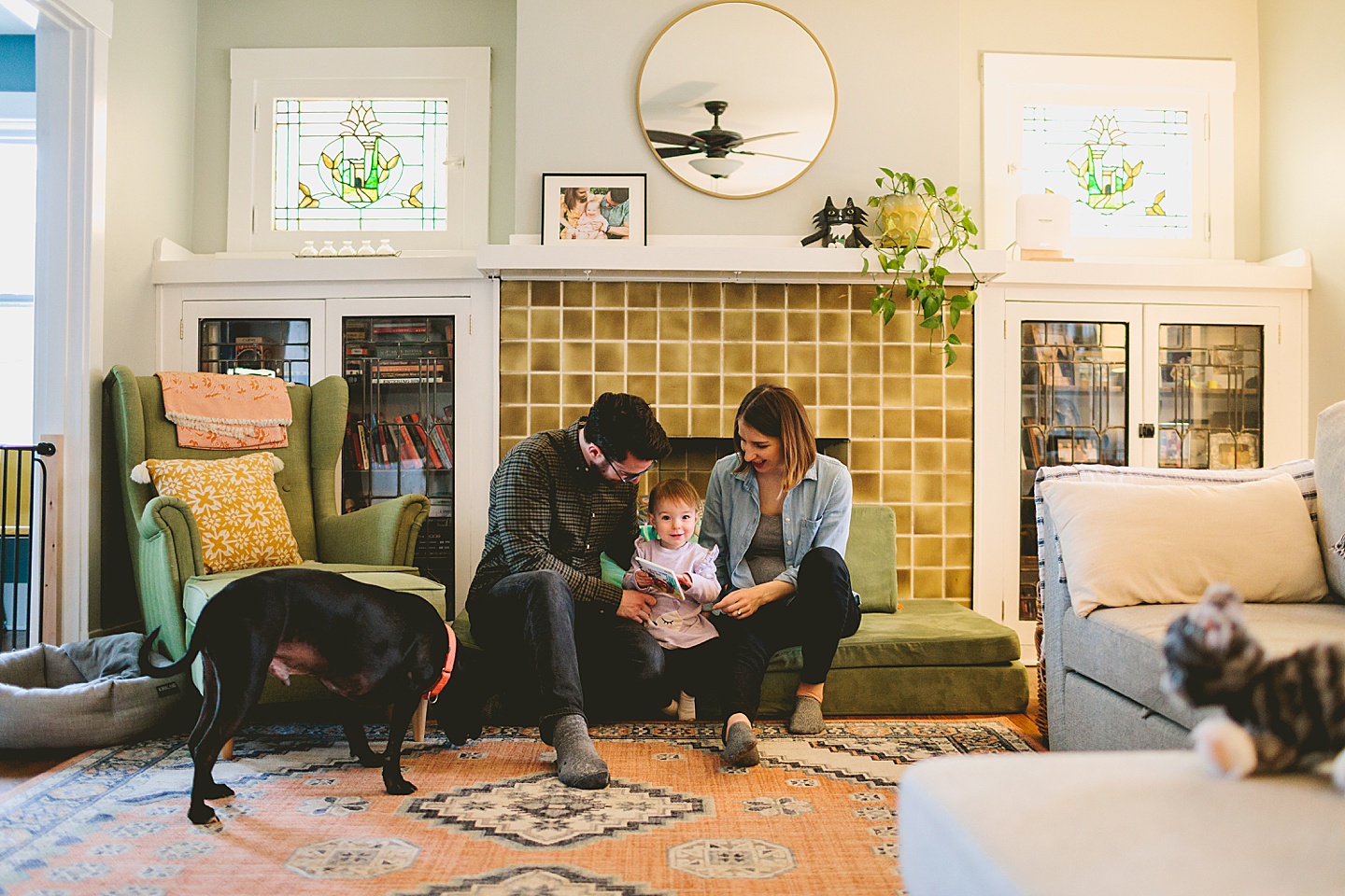 parents reading a book to a toddler in front of fireplace