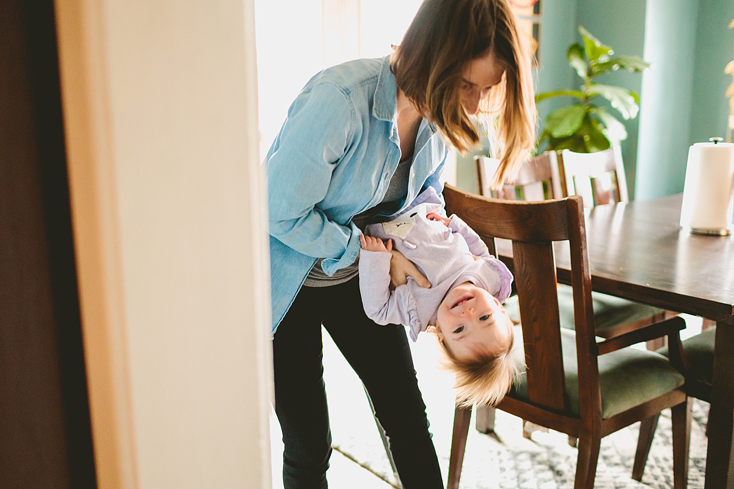 mom holding laughing toddler upside down