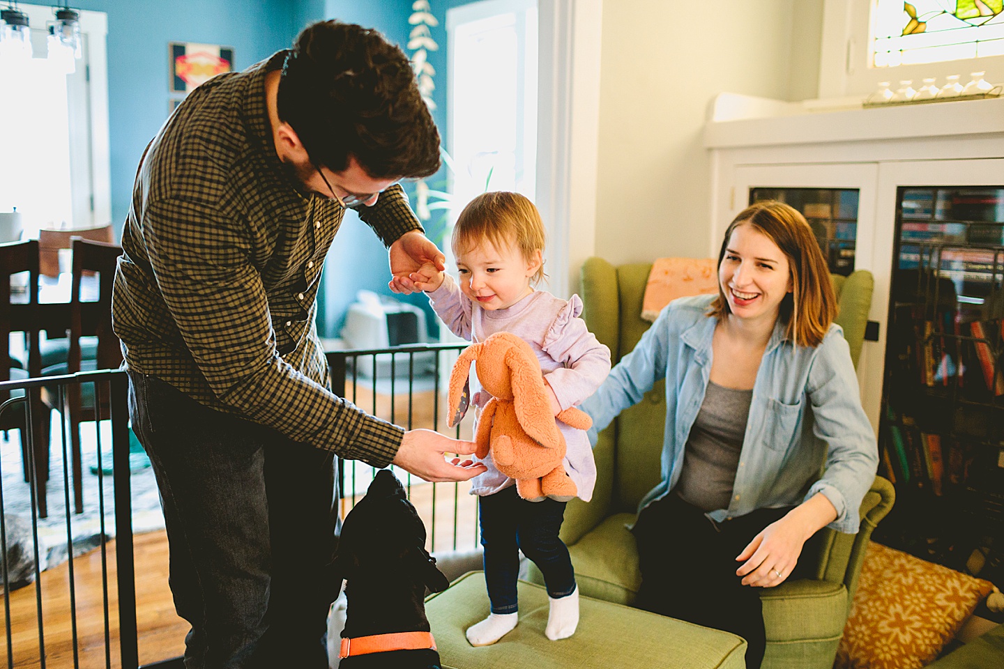 parents helping toddler walk on the couch