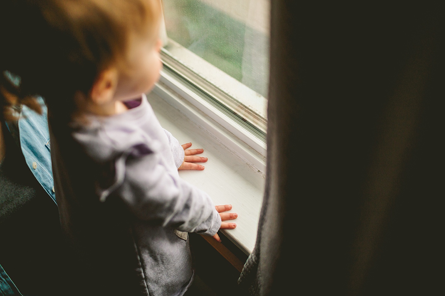 little hands on windowsill looking out window