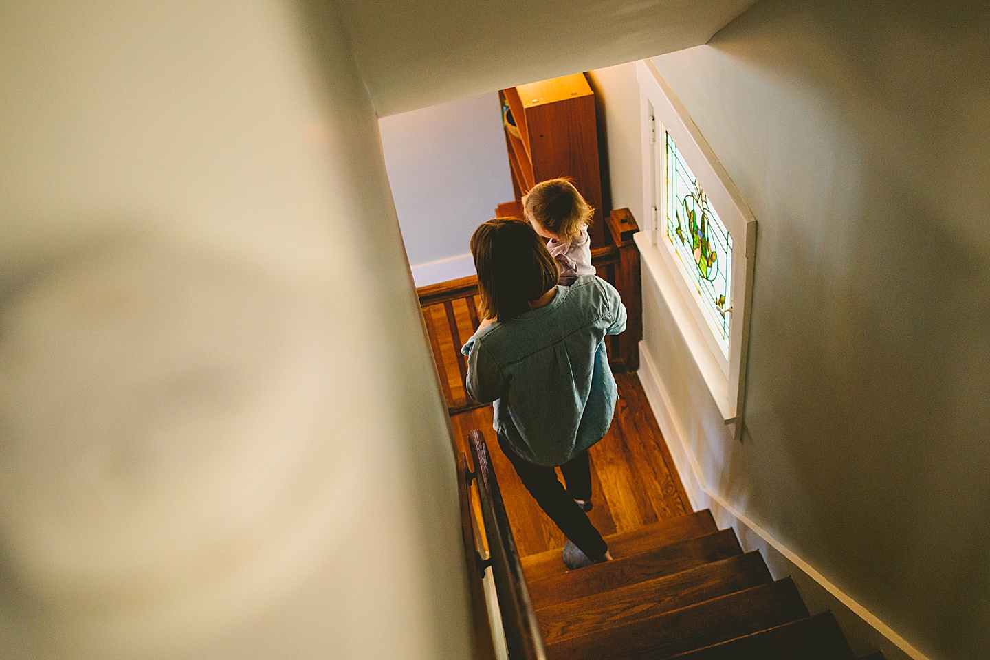 mother carrying daughter down the stairs