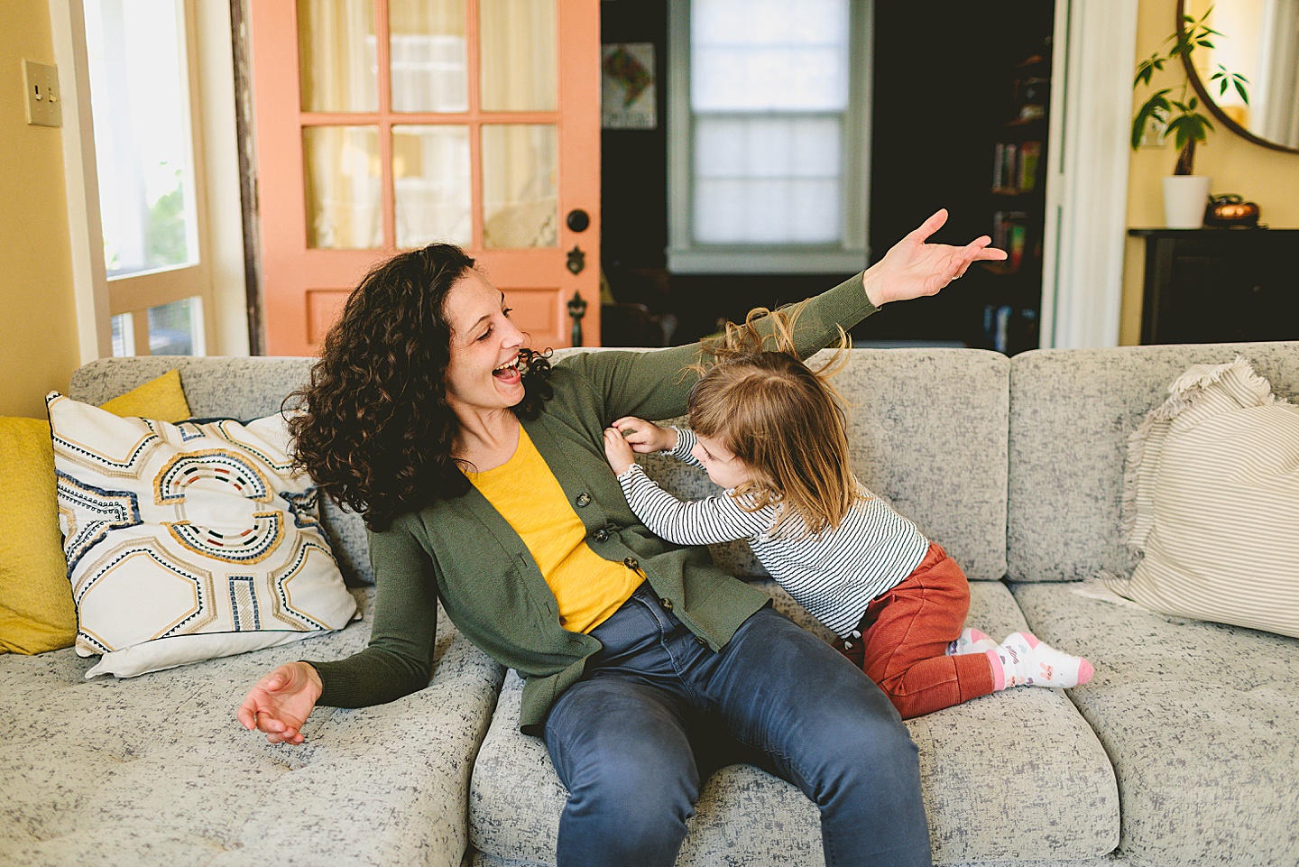 Mother and daughter wrestling on couch