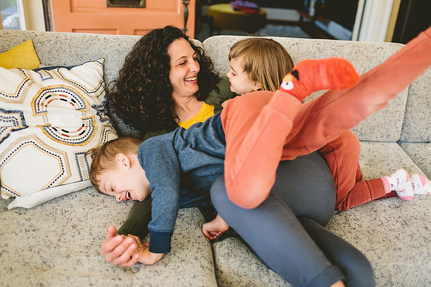Mom wrestling with kids on couch and laughing