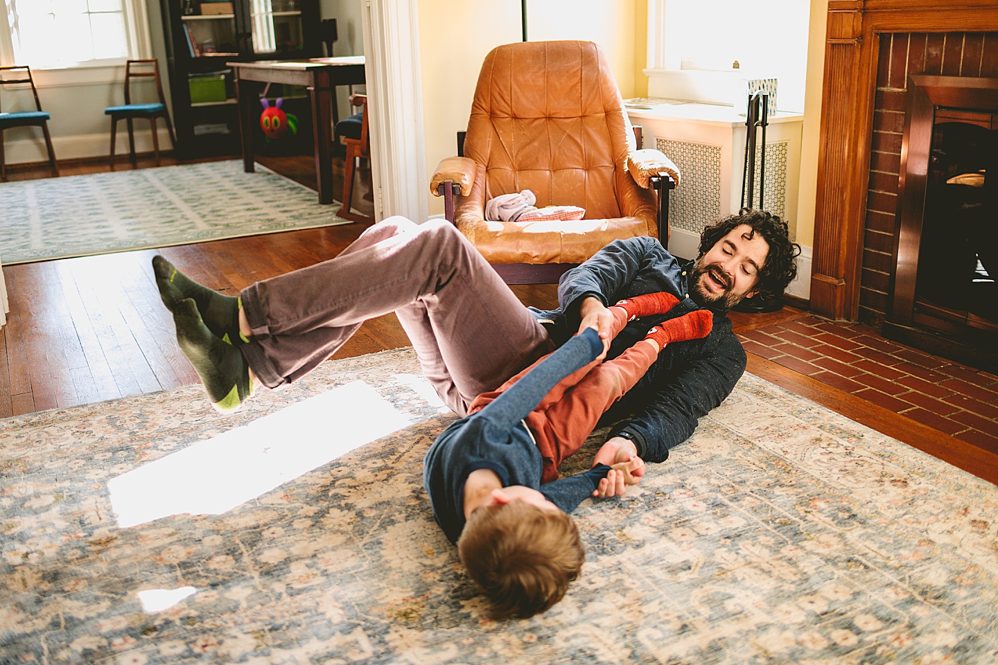 Father and son wrestling on ground in living room laughing