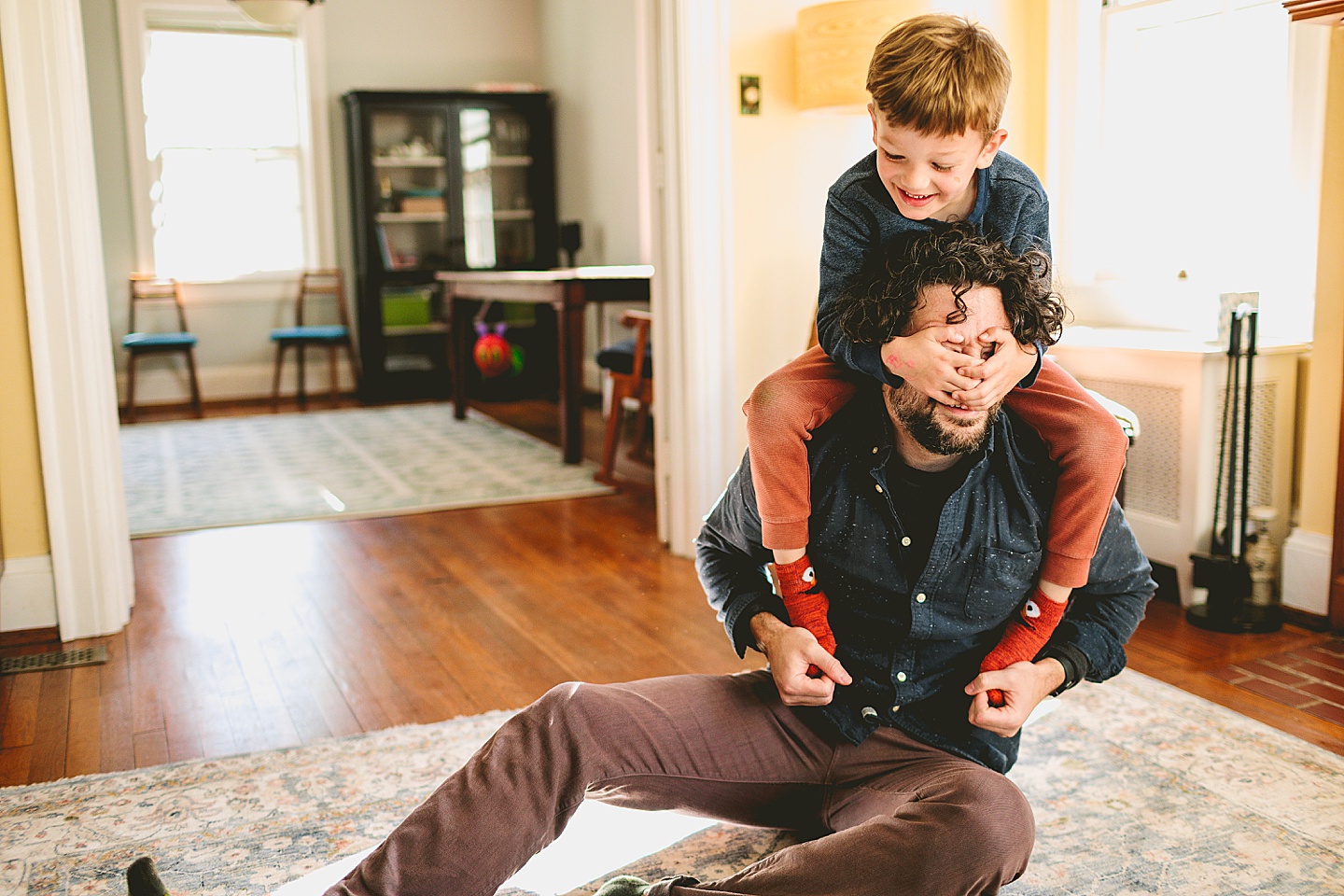 Father and son wrestling on ground in living room laughing