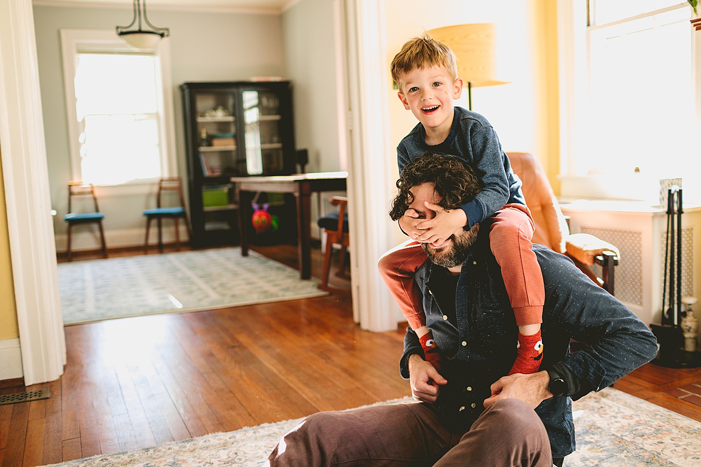 Father and son wrestling on ground in living room laughing