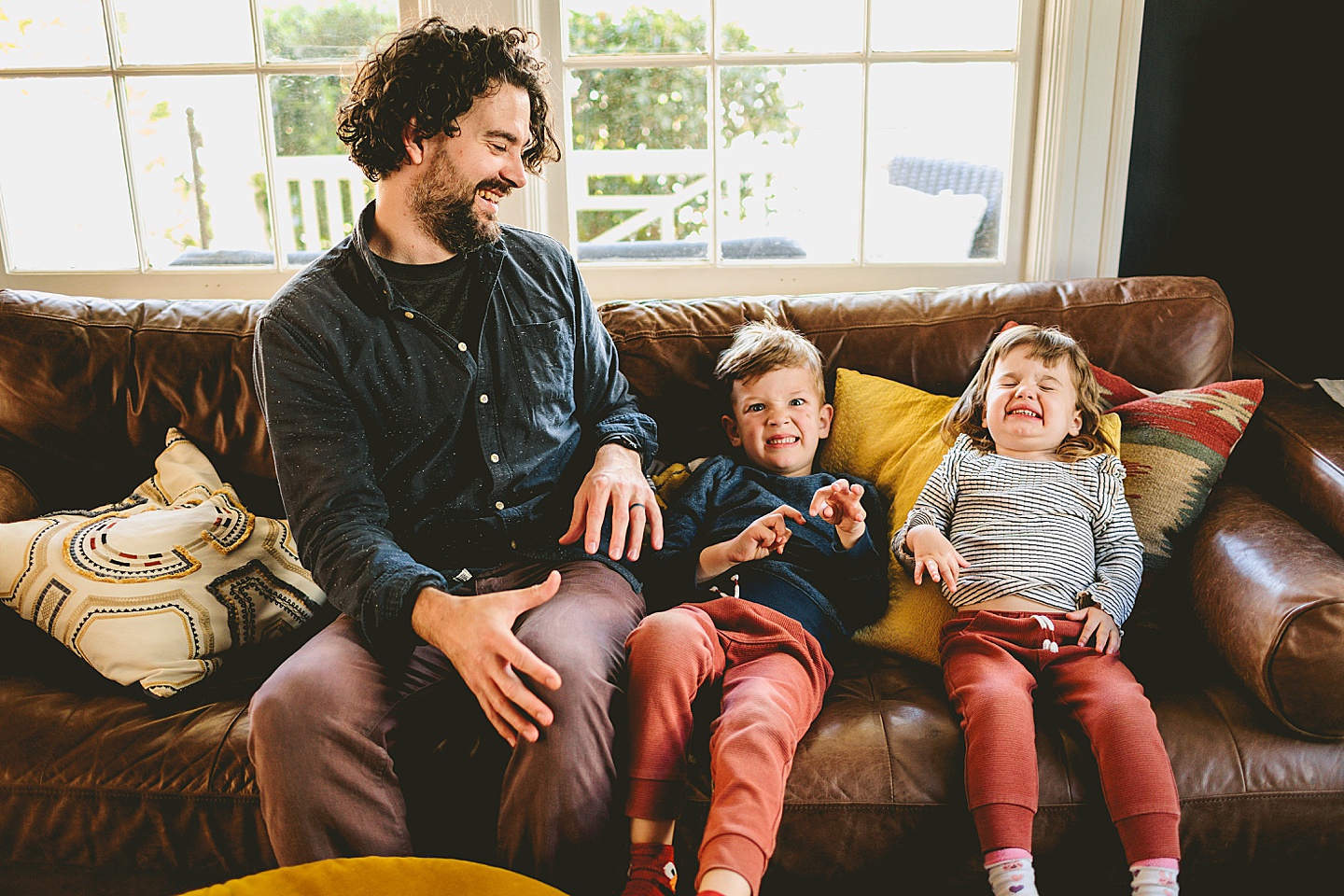 Dad sitting with kids on the couch and kids pretending to be monsters