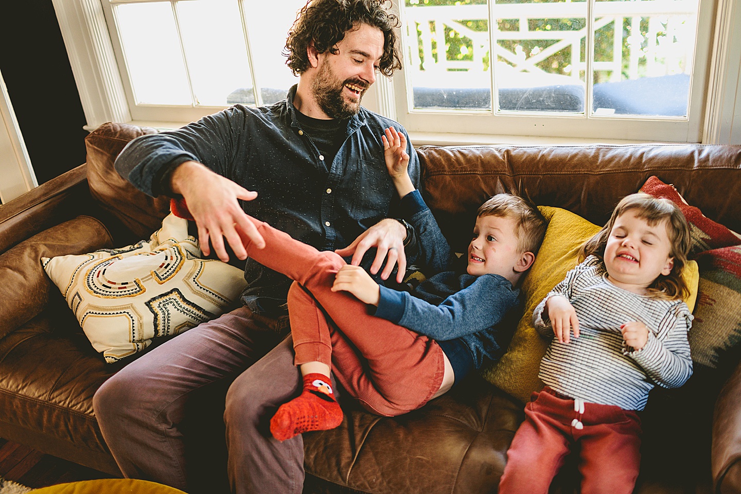 Dad sitting with kids on the couch and kids pretending to be monsters