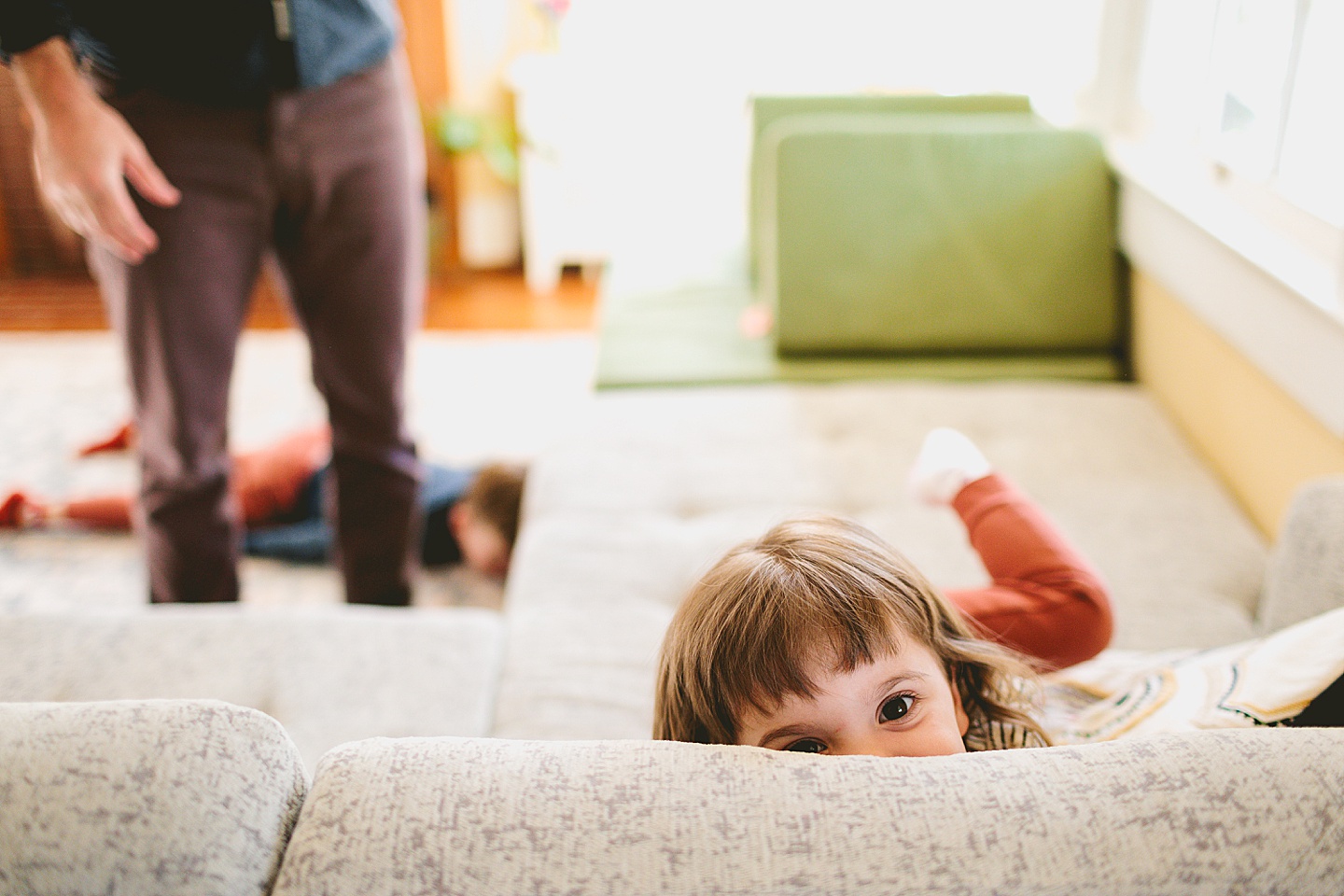 Girl smiling behind couch