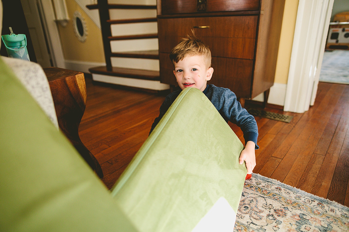 Kid holding green couch cushion