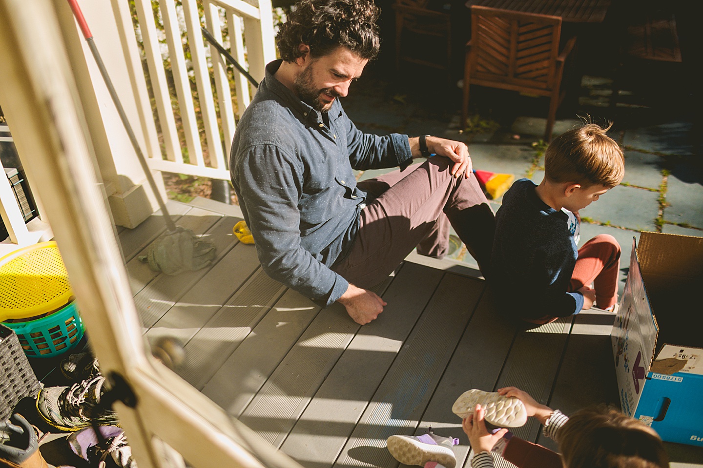 Dad helping kids put on shoes on the deck