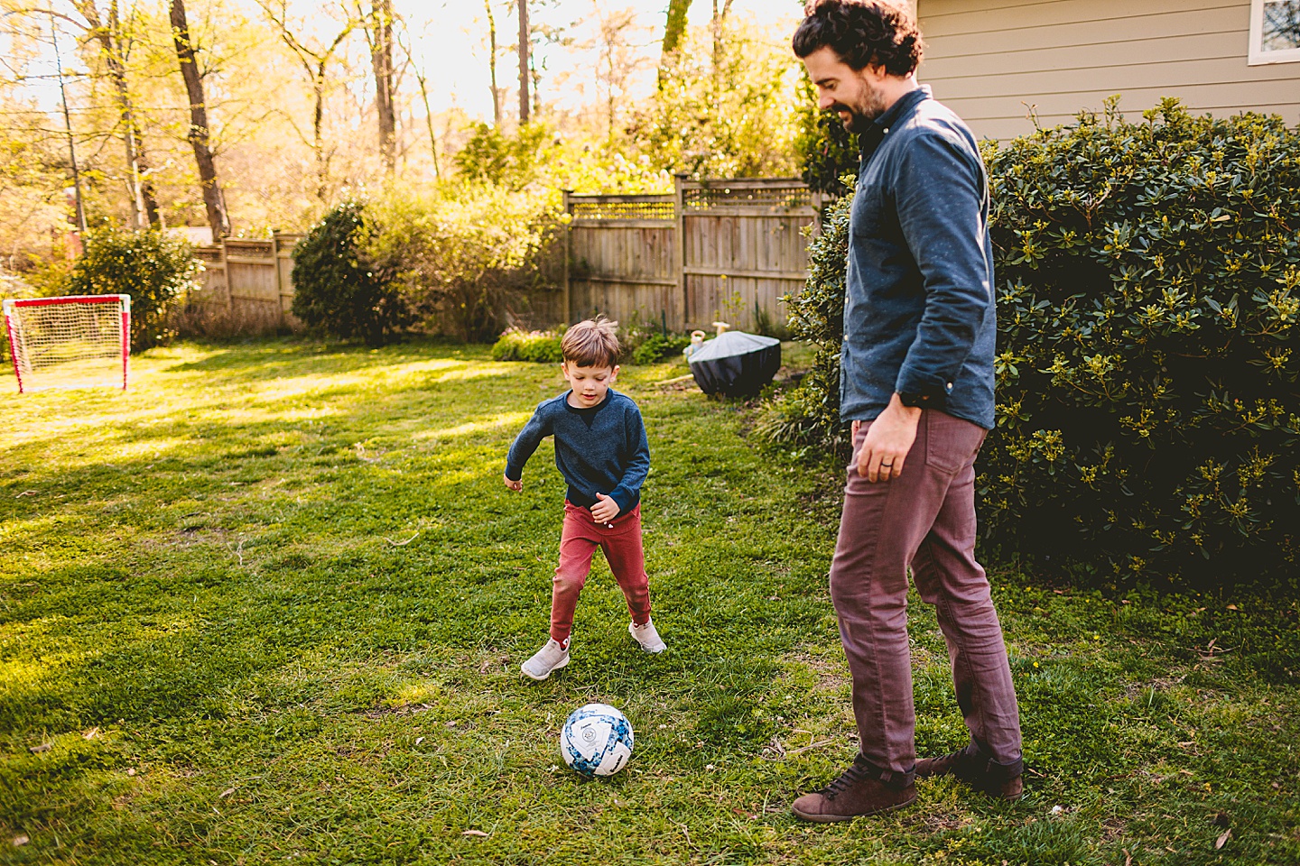 Boy playing soccer in the yard with Dad in Durham