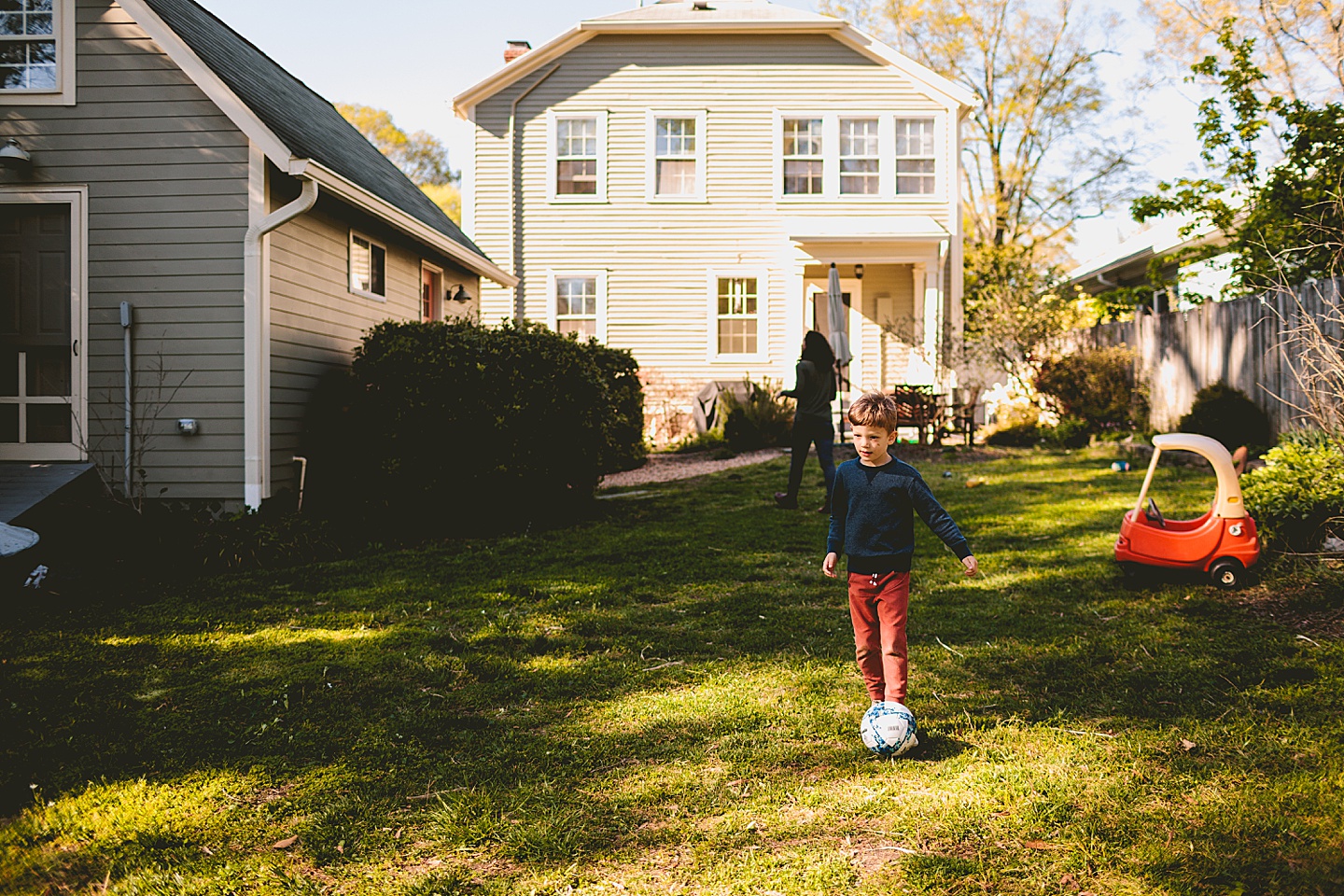 Boy kicking soccer ball in the backyard