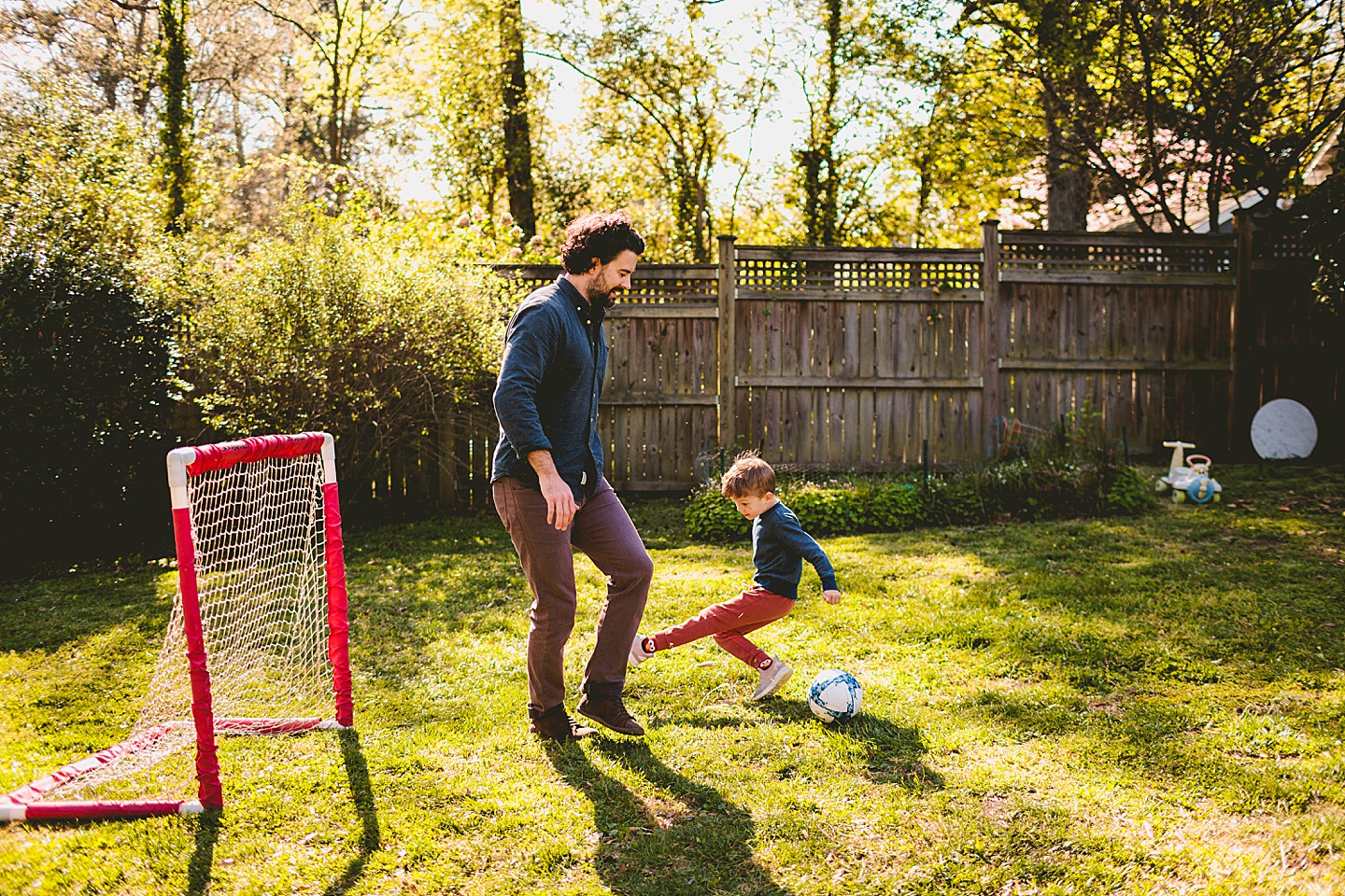 Boy playing soccer in the yard with Dad in Durham