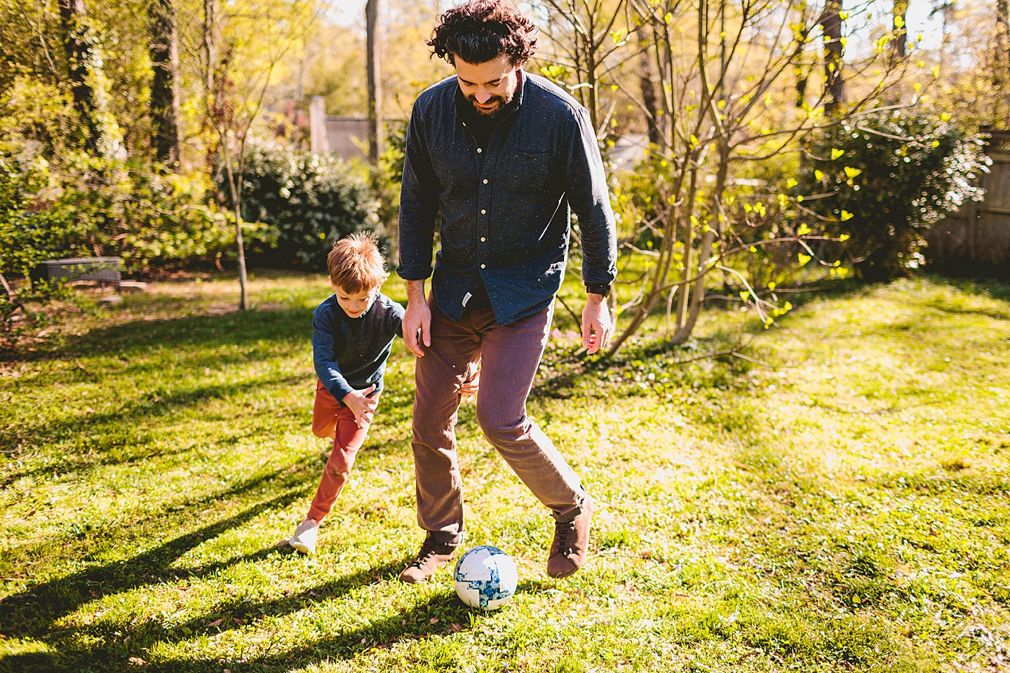 Boy playing soccer in the yard with Dad in Durham