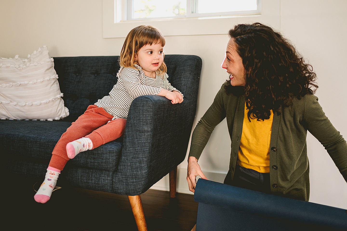 Girl sitting on couch and smiling at her mom