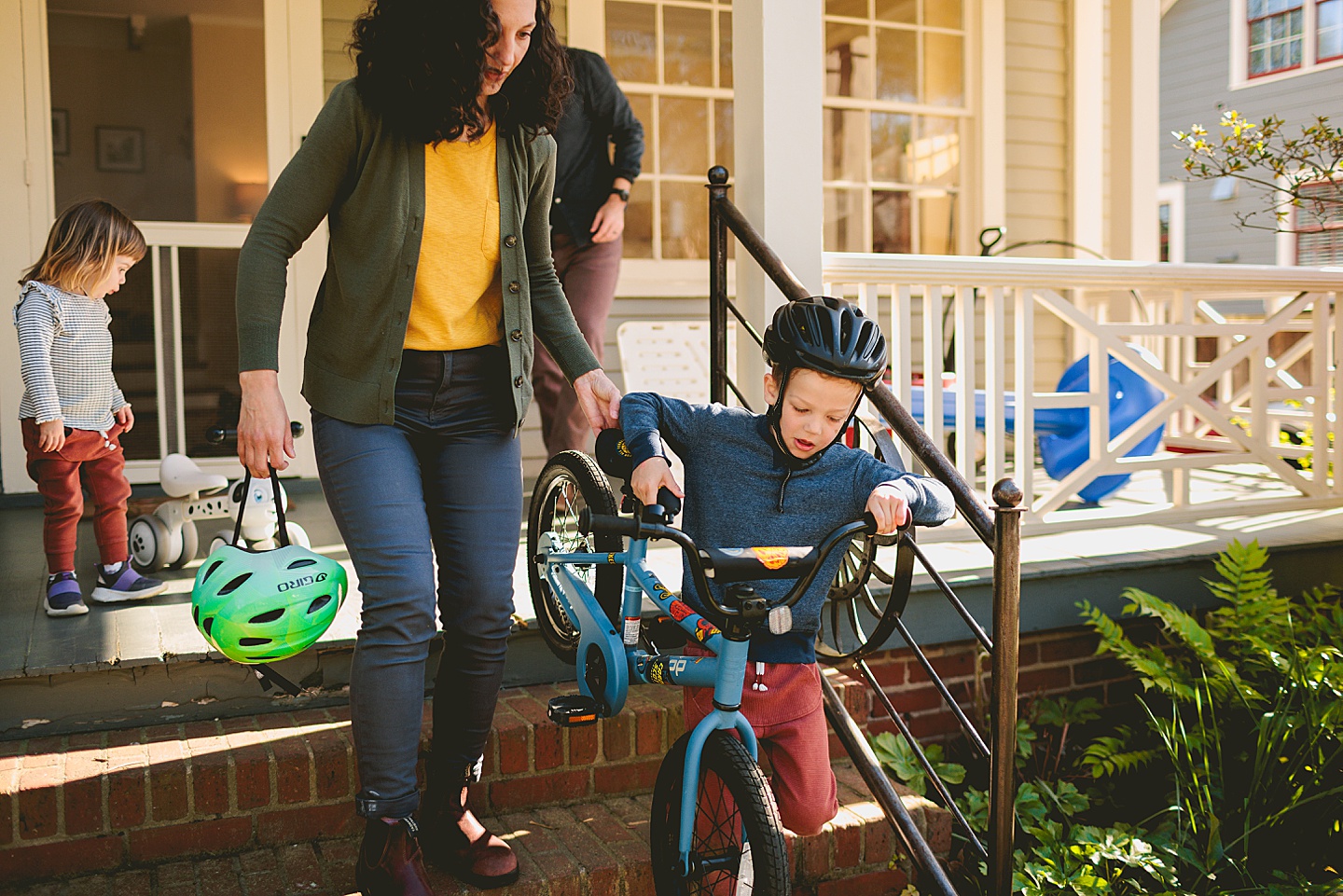 Boy carrying his bike down the steps of his house