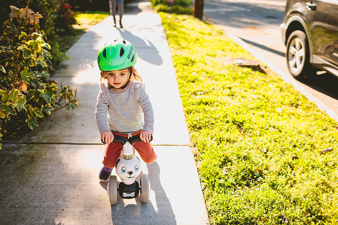 Girl riding puppy bike down sidewalk
