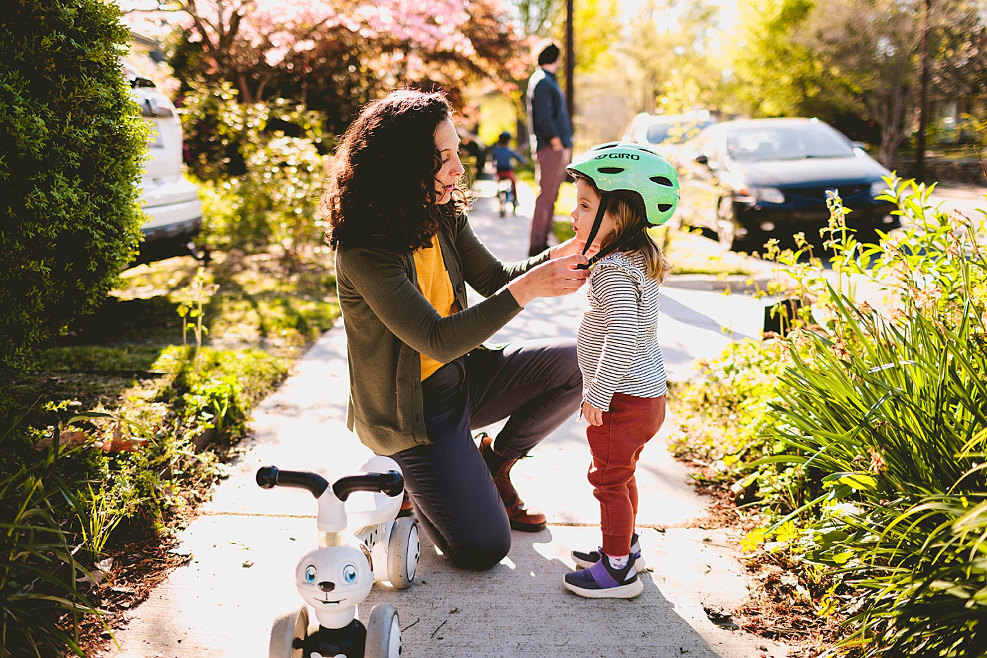 Mom helping daughter put her bike helmet on again