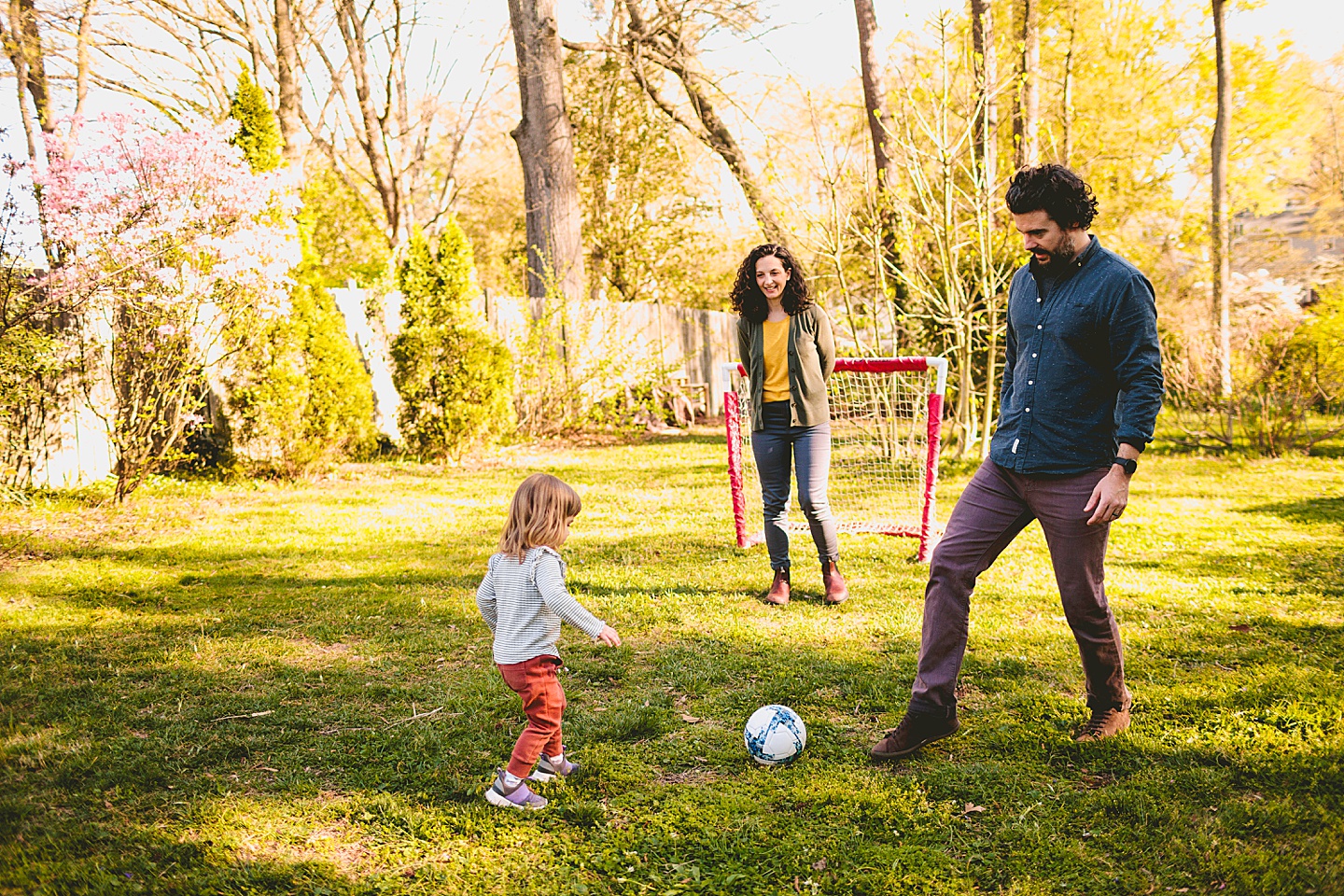 Girl playing soccer with family in the backyard