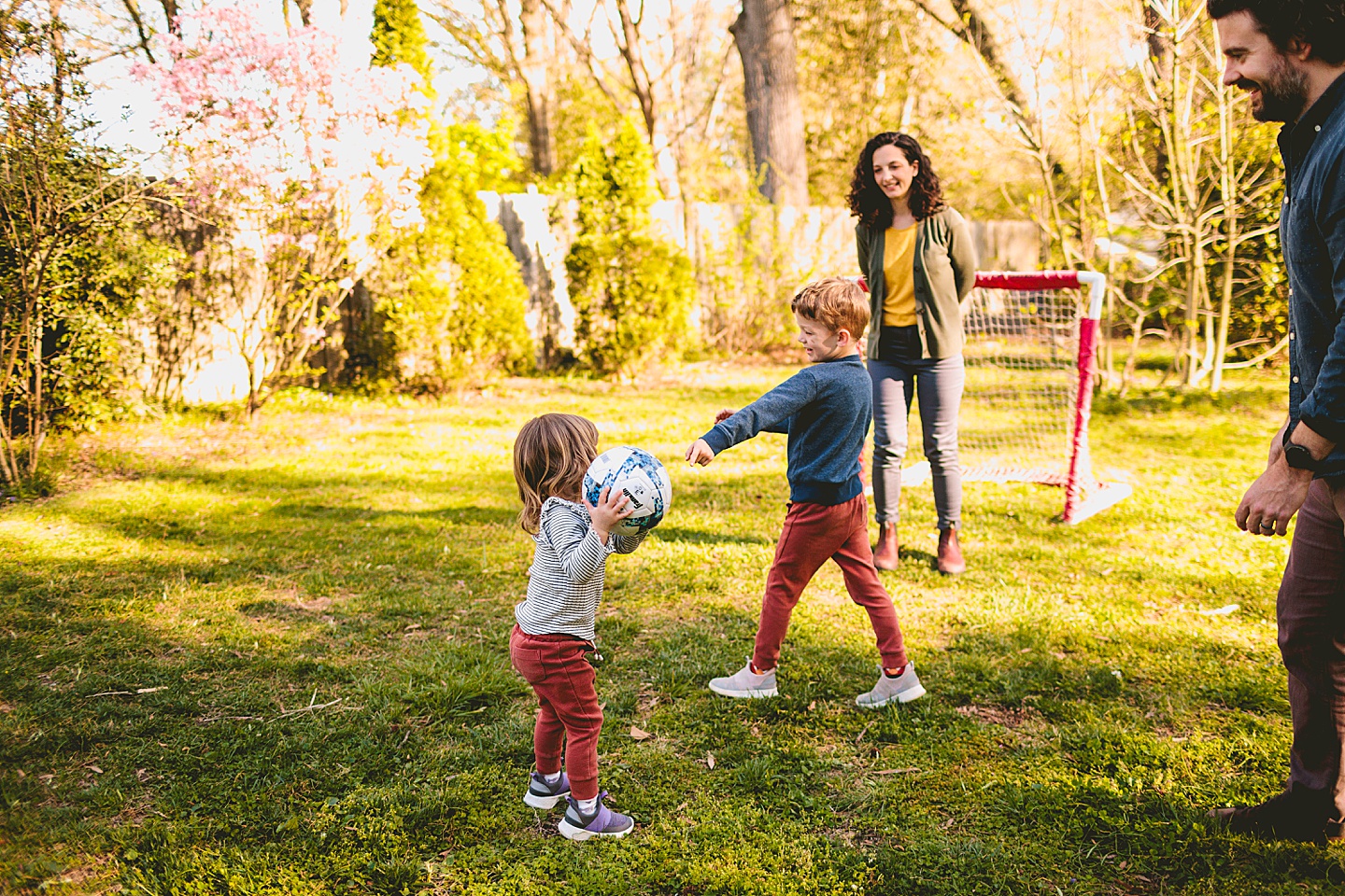 Girl playing soccer with family in the backyard