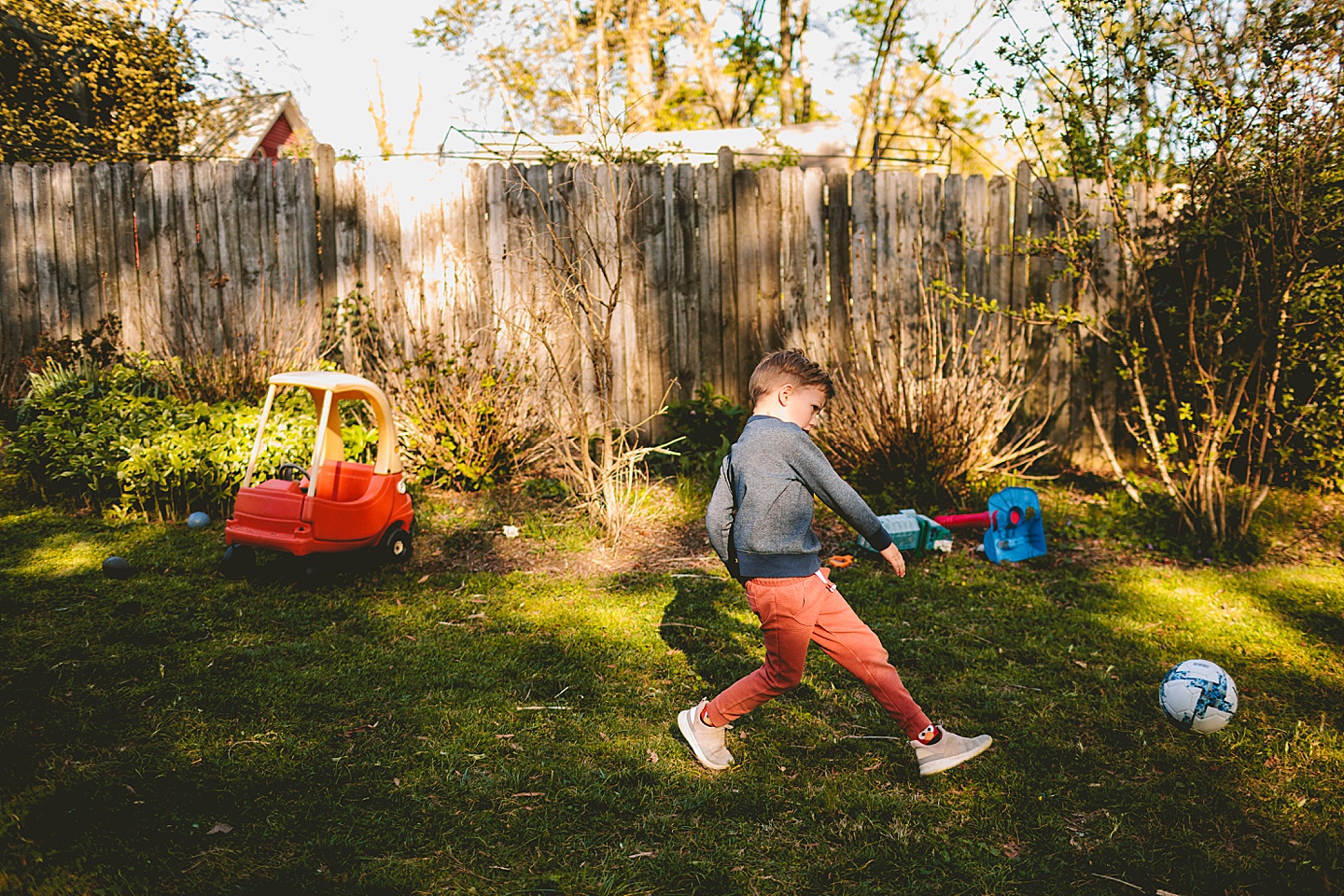 Boy kicking soccer ball in yard