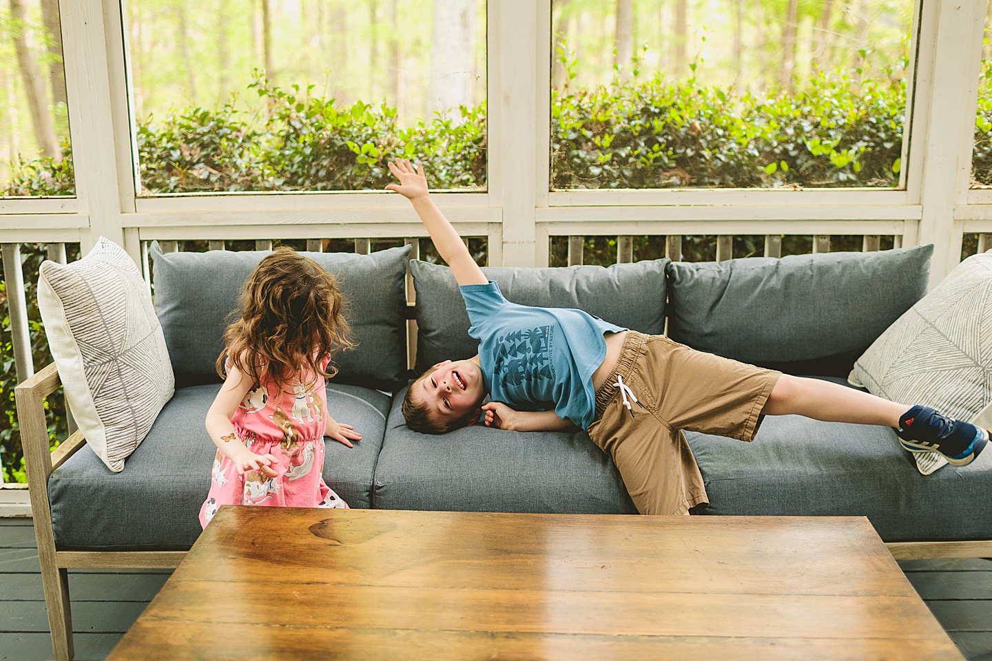 Siblings goofing around on screened in porch in Raleigh during family photos