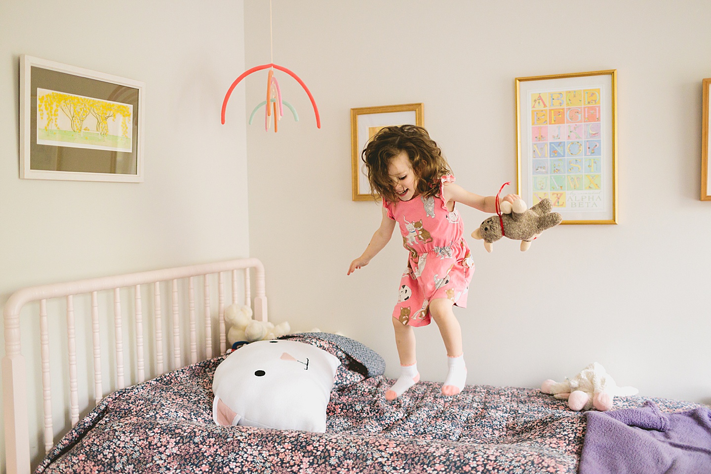 Girl jumping on a bed with cat doll and cat pillow