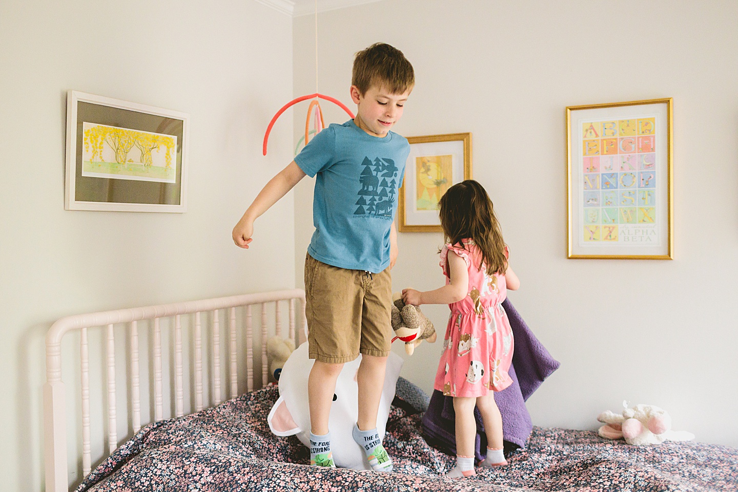 Brother and sister jumping on a bed with cat doll and cat pillow