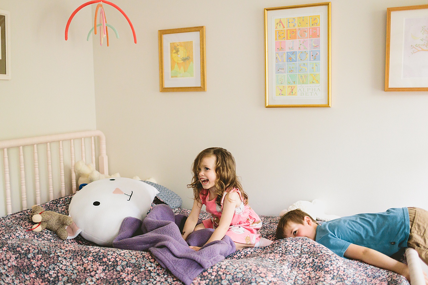 Brother and sister jumping on a bed with cat doll and cat pillow