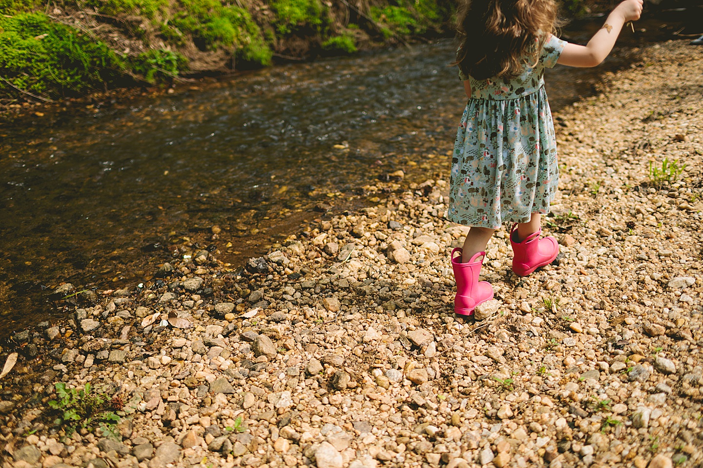 Girl walking along creek wearing pink rainboots